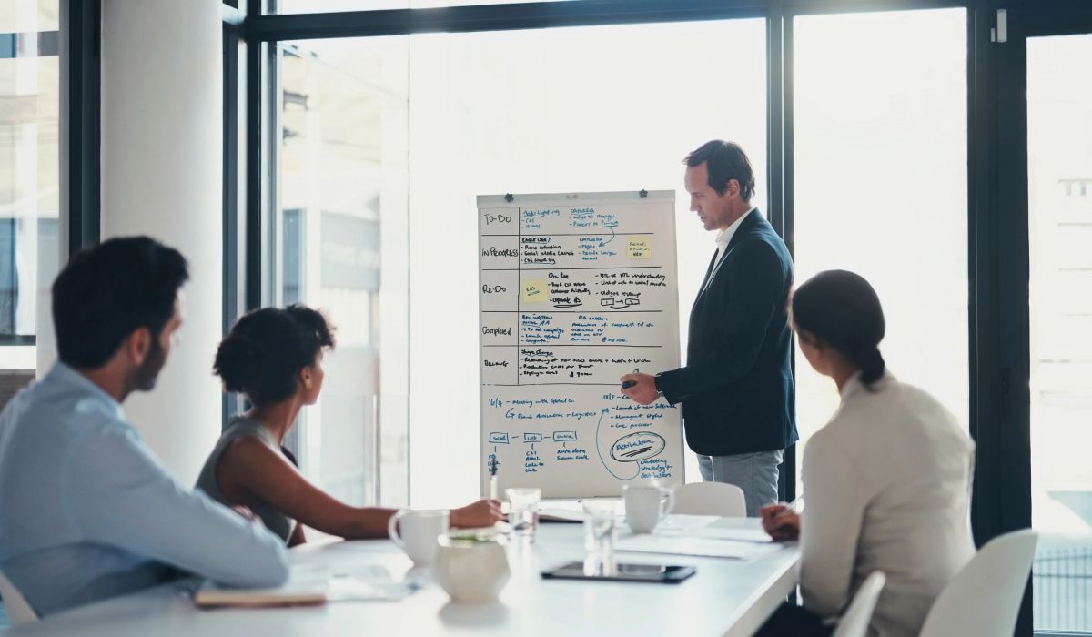 Un coach qui illustre un processus de vente au tableau avec une équipe